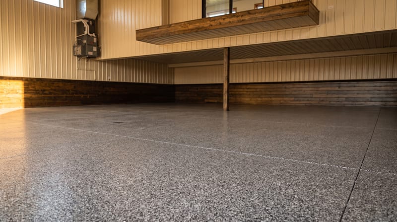 A finished ¼-inch flake epoxy floor in a workshop garage, the chip broadcast dense and even across the slab.